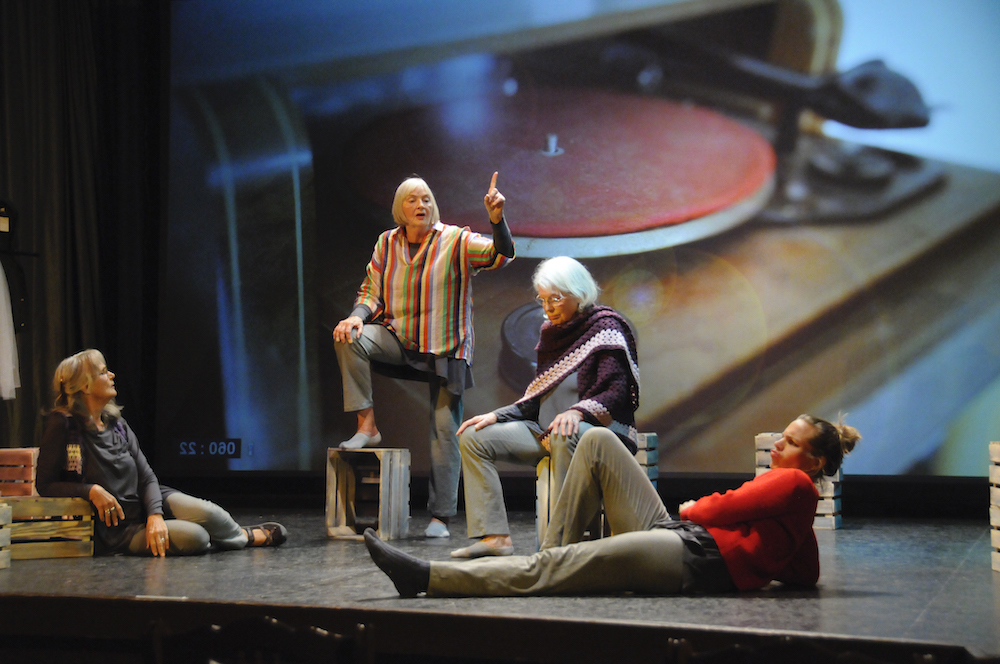 Vier Frauen im Vordergrund, im Hintergrund das große Bild eines Plattenspielers